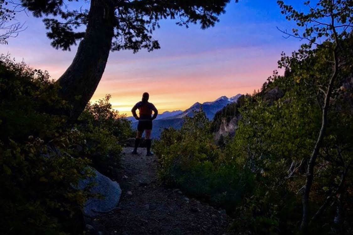 A lone hiker watching a vivid sunrise from a mountain trail